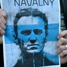 Blue flyer held with human hands displaying a sketch of Alexei Navalny's face 
