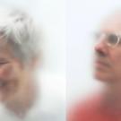 side by side images. Left woman facing left with gray hair, smiling looking down. Right: balding man with glasses looking up. Both are behind semitransparent white scrim.