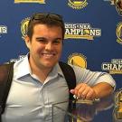 Danny Seidel stands in front of a Golden State Warriors background.