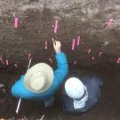 Two geologists stand in a trench looking at evidence for earthquakes in the layers of soil.