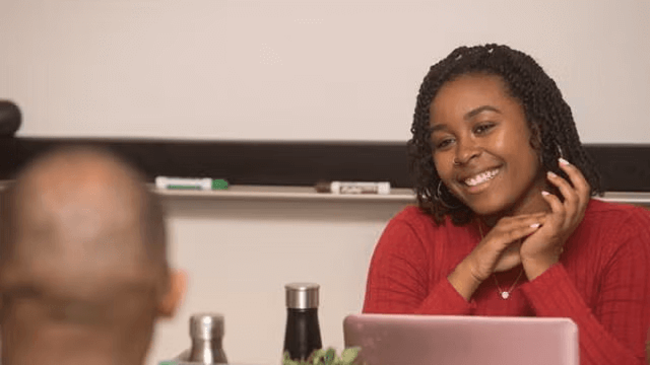 A student smiling with another student in front of her laptop