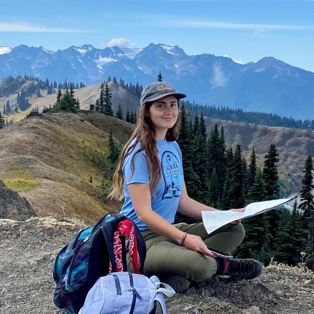Caden Williams sits on a rock in front of a mountain view. 