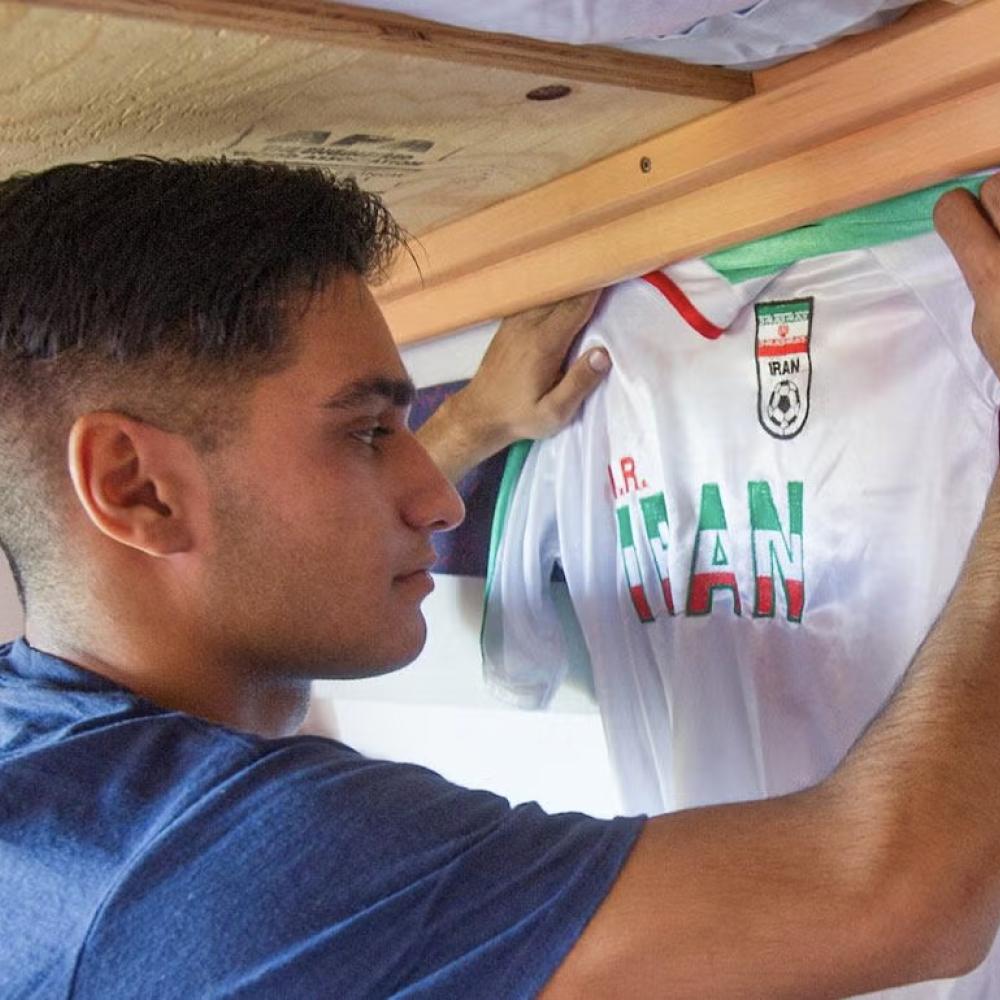 Student hanging Iran football club jersey in dorm