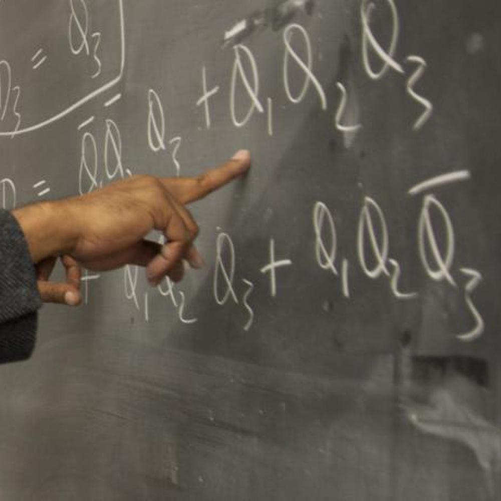 Finger pointing to equation on blackboard