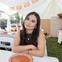 Smiling young woman seated at a decorated outdoor tent table, arms folded