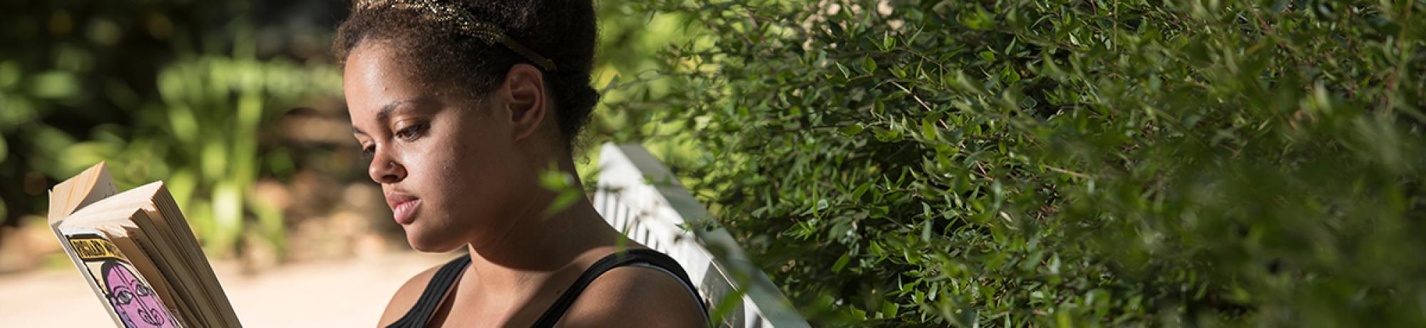 Photo: young woman sitting on a bench reading a book